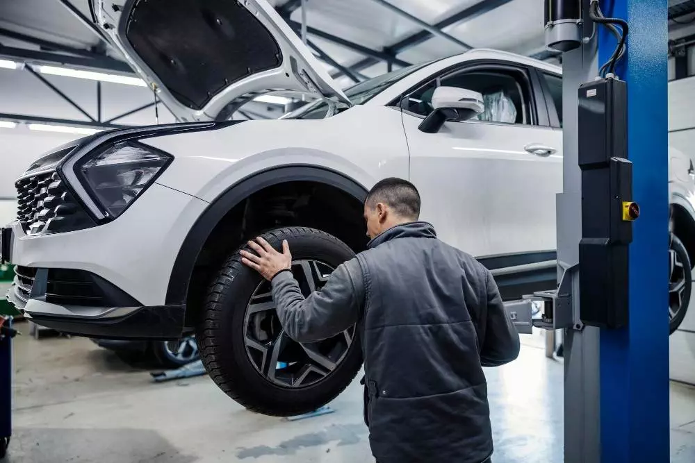 auto mechanic changing old tires lifted car