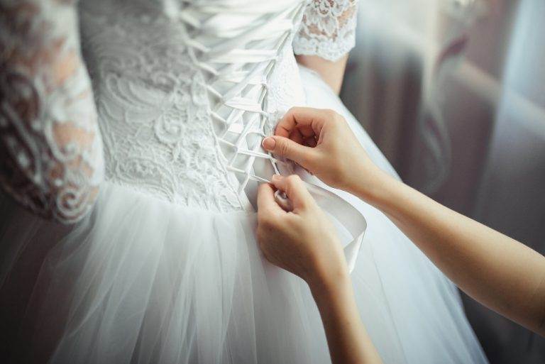 bridesmaid makes bow knot back brides wedding dress